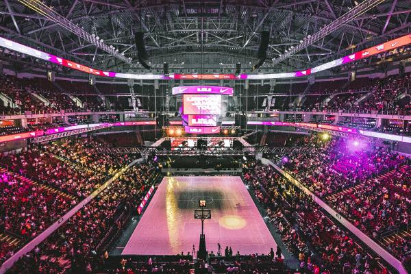 Picture of a full basket ball stadium lit with purple and pink lights