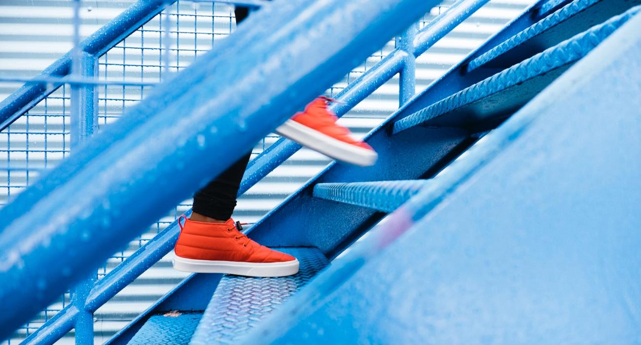 Close up shot of person in red shoes running up blue metal stairs