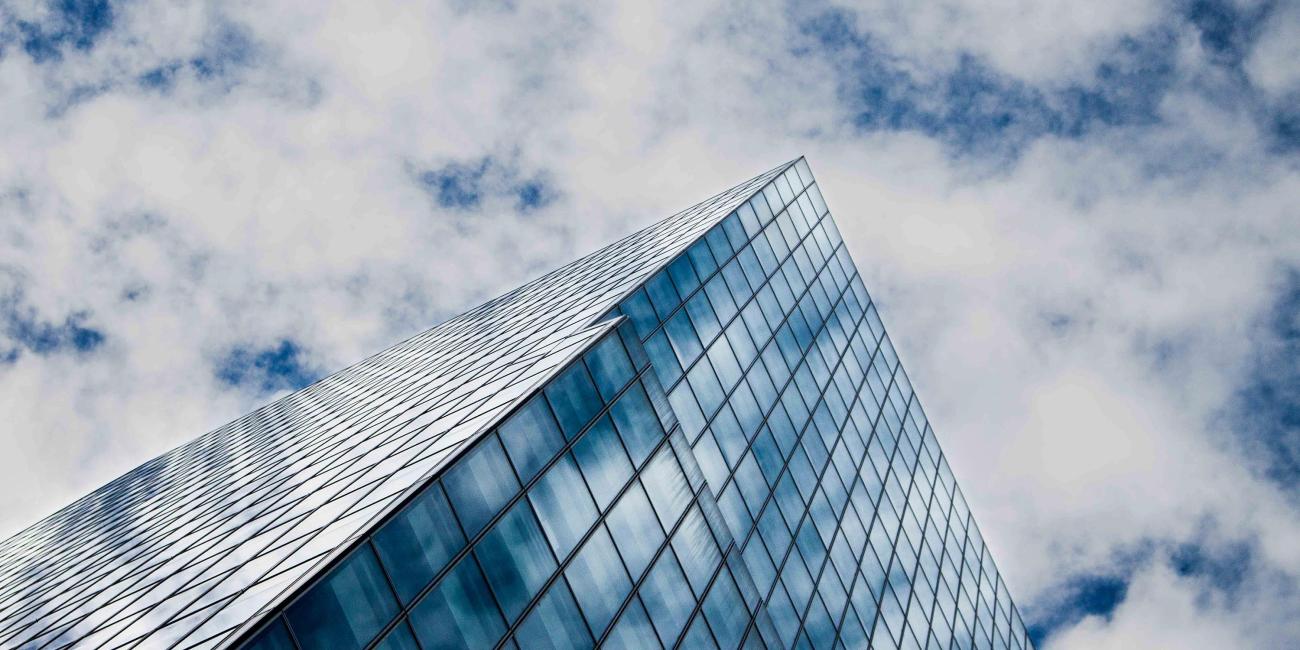Glass building reflects a cloudy blue sky