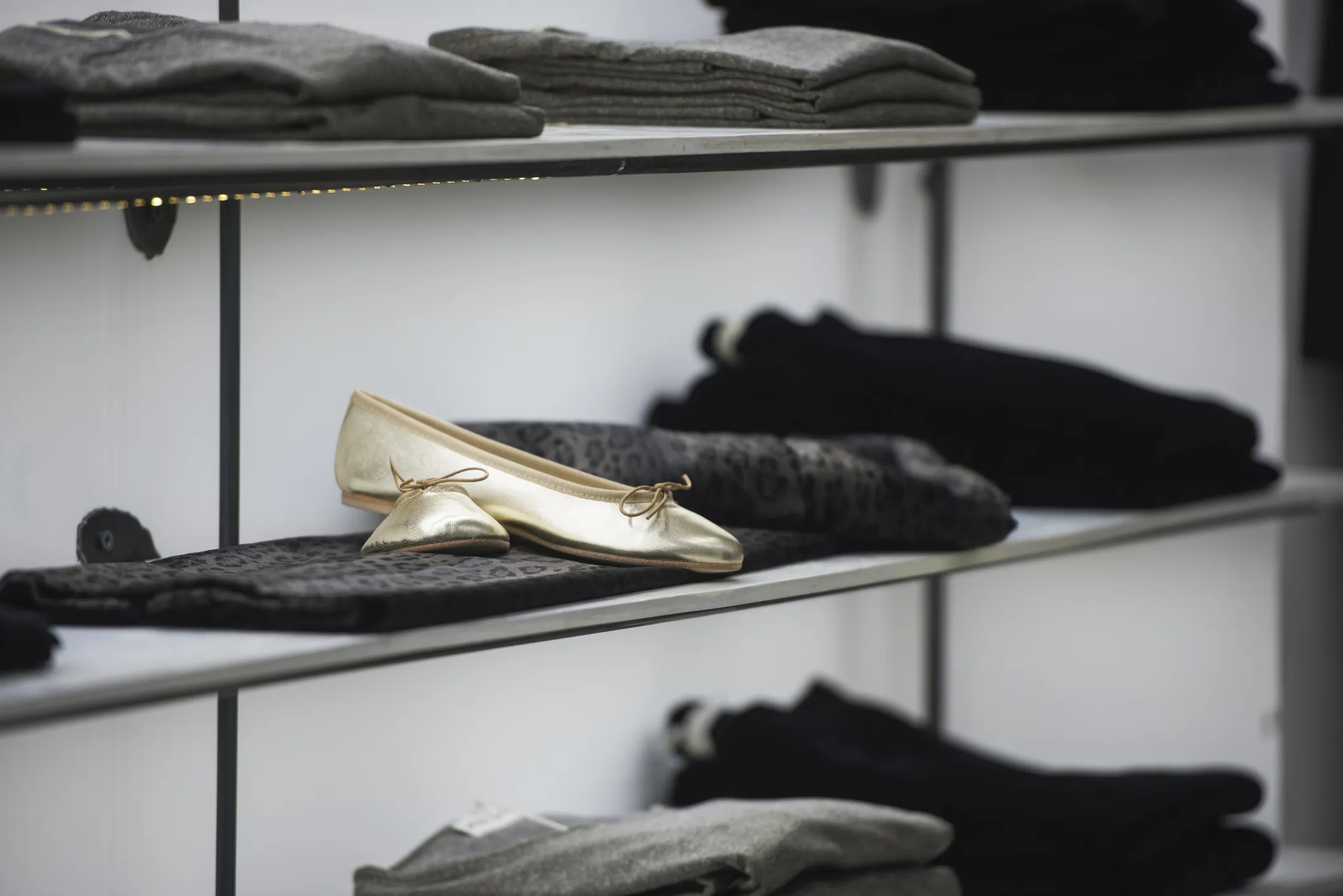 Gold flats displayed on folded gray clothing in a store.